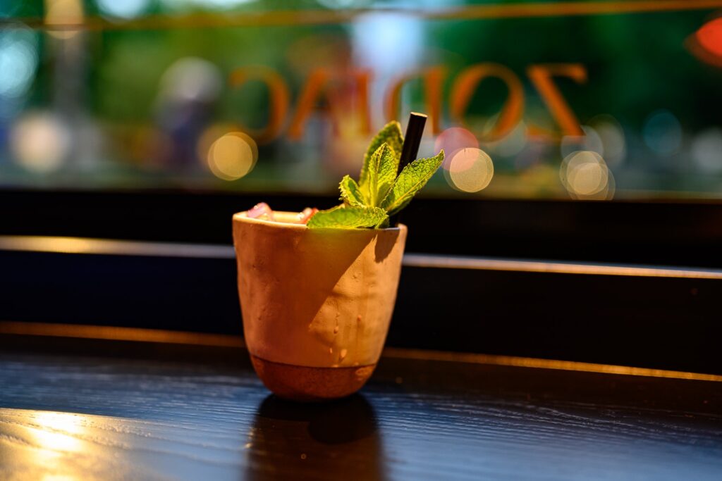 A cocktail with fresh mint in front of the Zodiac sign
