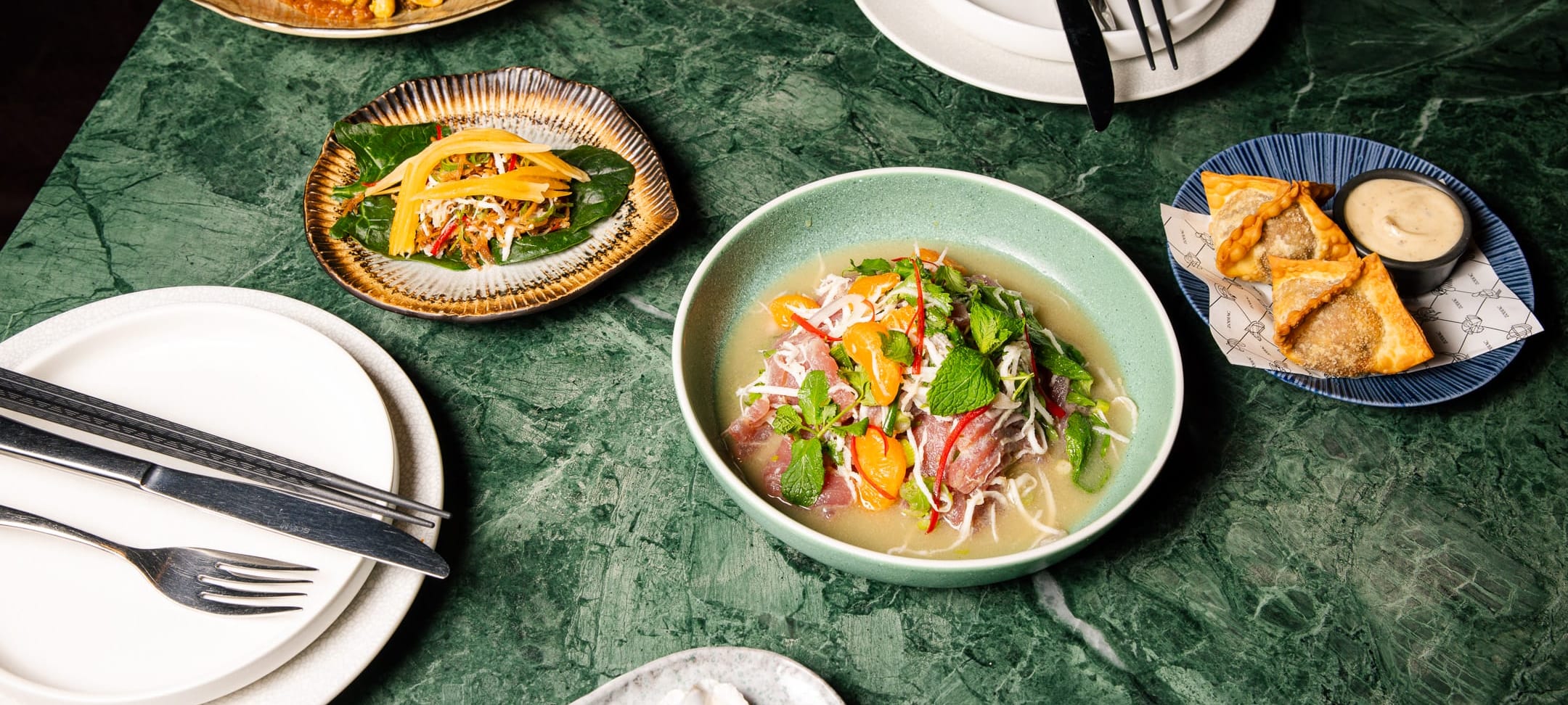Zodiac lunch dishes on green marble: spinach leaf, a fragrant broth and crispy pastries