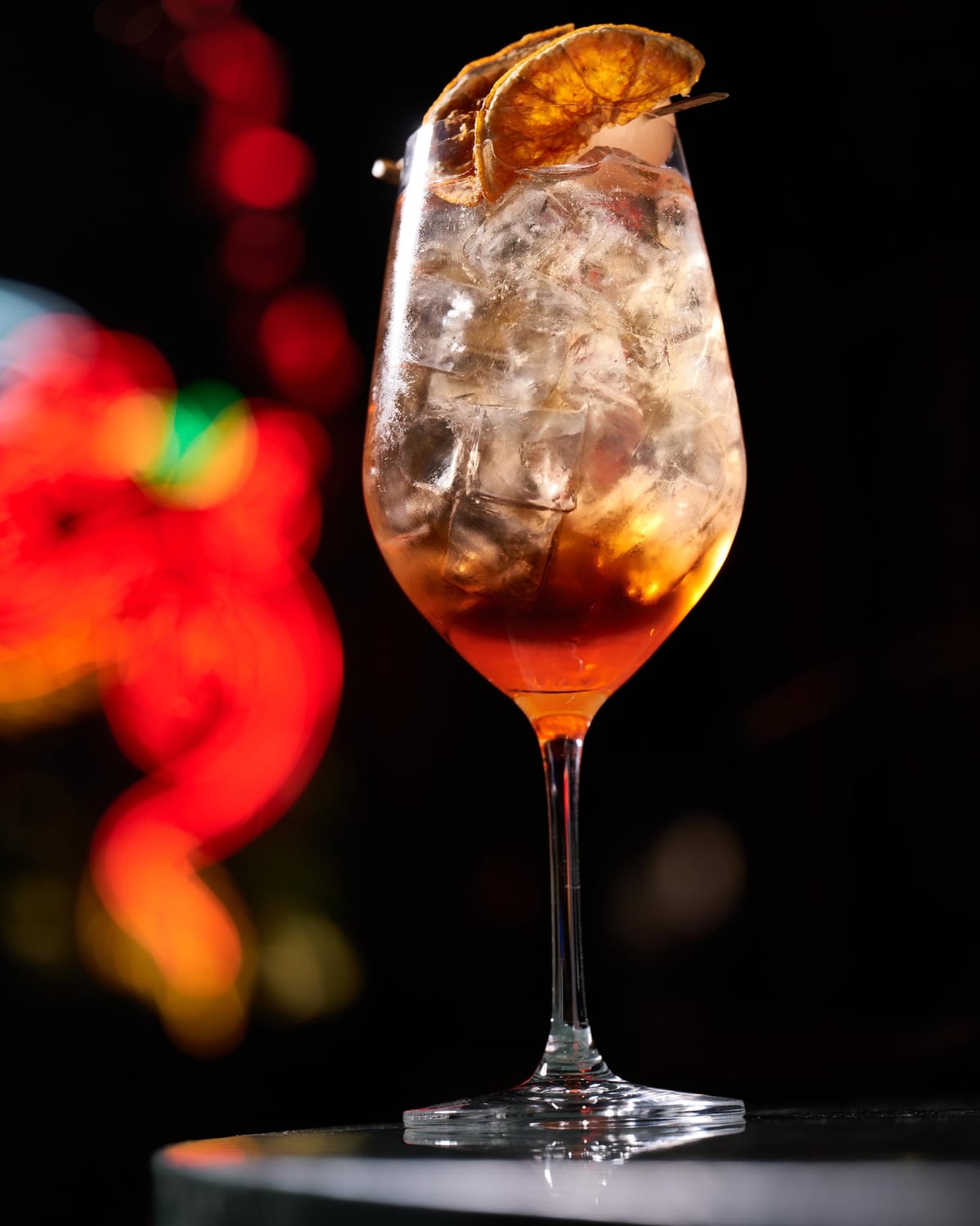 A spritz cocktail glowing in front of the neon dragon at Zodiac